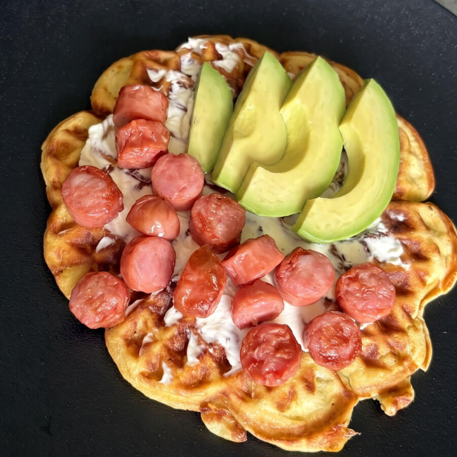 Waffles de maduro preparados con Salchicha Desayuno Premium Fazán, queso crema y láminas de aguacate, servidos como un desayuno fácil y lleno de sabor.