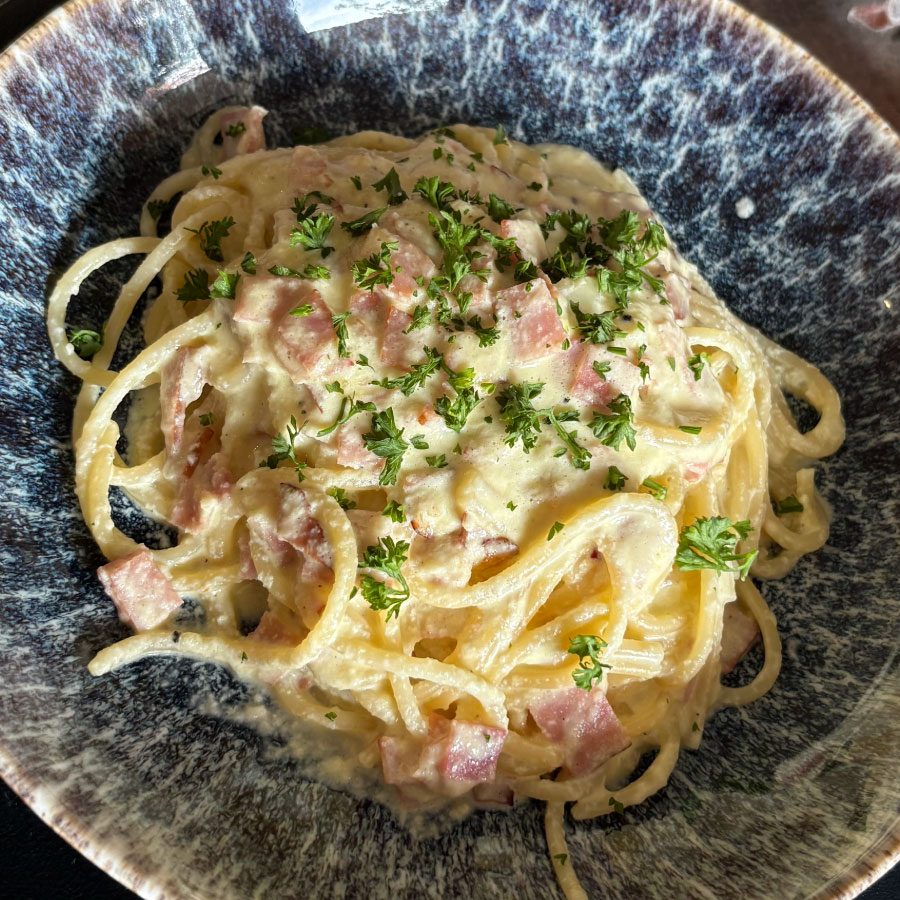 Espaguetis con Jamón Premium Fazán y Tocineta Ahumada Fazán en salsa cremosa, acompañados con queso parmesano rallado y perejil fresco.